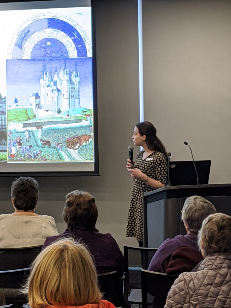 Brunette in a typewriter dress presenting a photo of a castle from a Book of Hours.